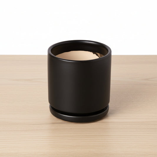 Black cylindrical container with beige interior on a white background
